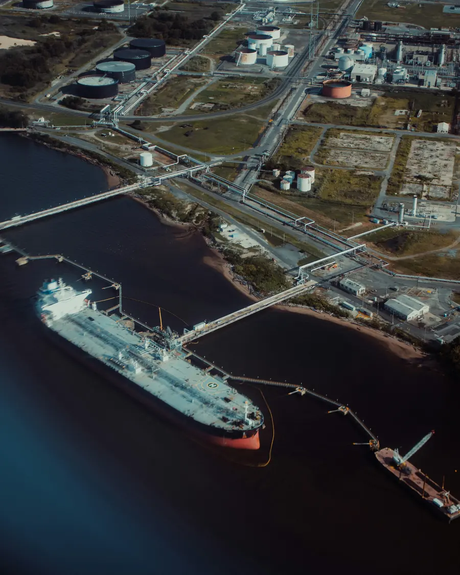 Aerial view of a tanker berthed at a marine terminal, with pipelines leading to a storage facility